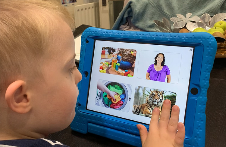 Photograph of a child with Down syndrome learning early vocabulary by selecting pictures.