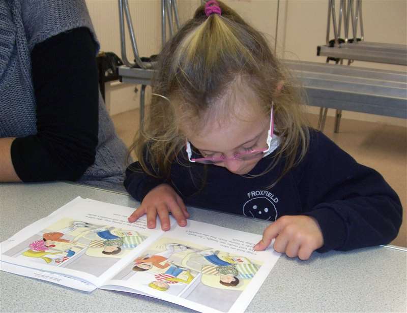 Photograph of a child reading in school.